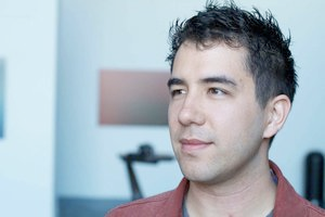 A portrait of a young man with light skin and short brown hair looking slightly to the left of the camera.
