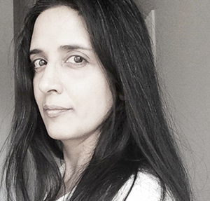 A three-quarter portrait of a young woman with very light skin and very dark, long, straight hair.