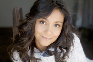 A portrait of a young woman with medium-brown wavy hair and brownish hazel eyes wearing a white sweater.
