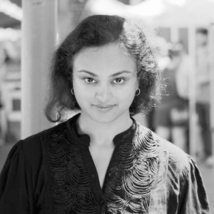 A grayscale portrait of a young woman with fluffy dark hair in a ponytail.