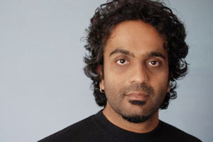 A portrait of a South Asian man with very curly dark hair and a goatee.