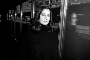 A grayscale portrait of a young woman with pale skin and dark hair, wearing a black turtleneck.